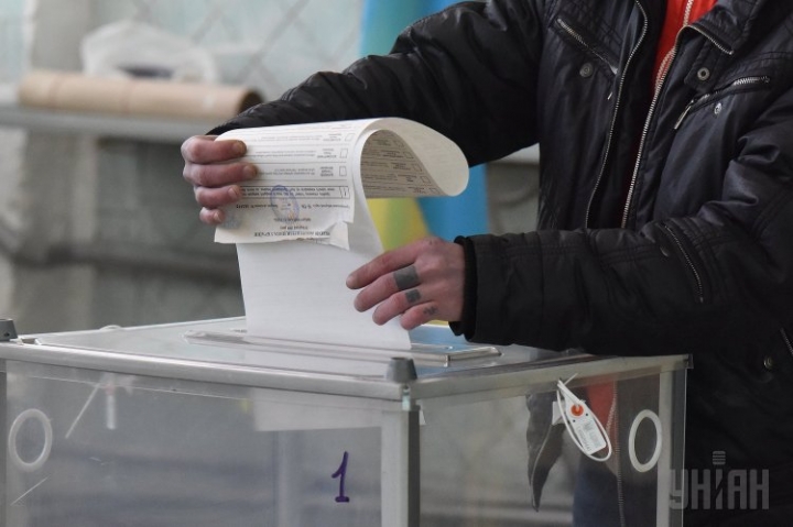 Чоловік вкидає бюлетень в урну для голосування. Фото: УНІАН
